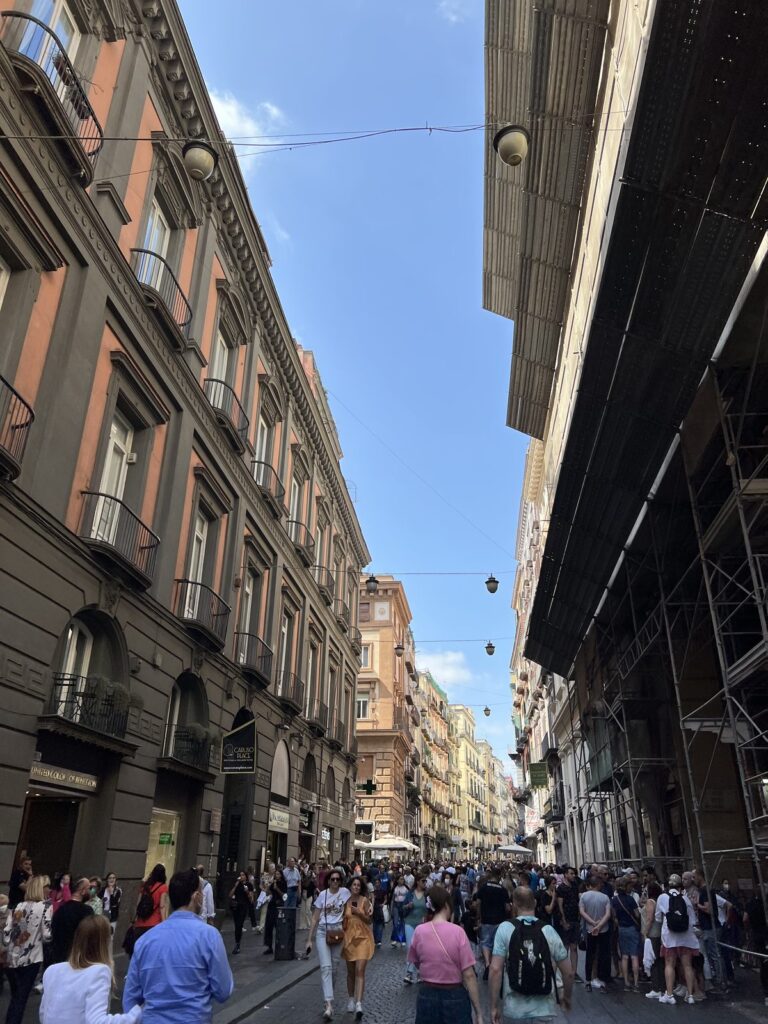 A busy shopping street crowded with people in central Naples