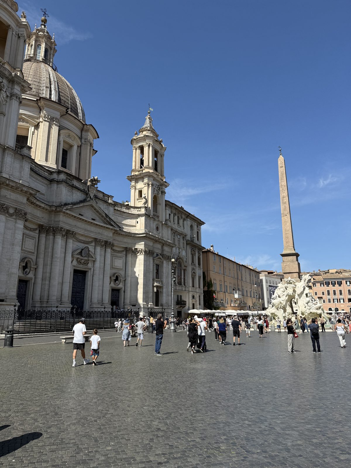 The open square of Piazza Navona in Rome with its church facade and obelisk