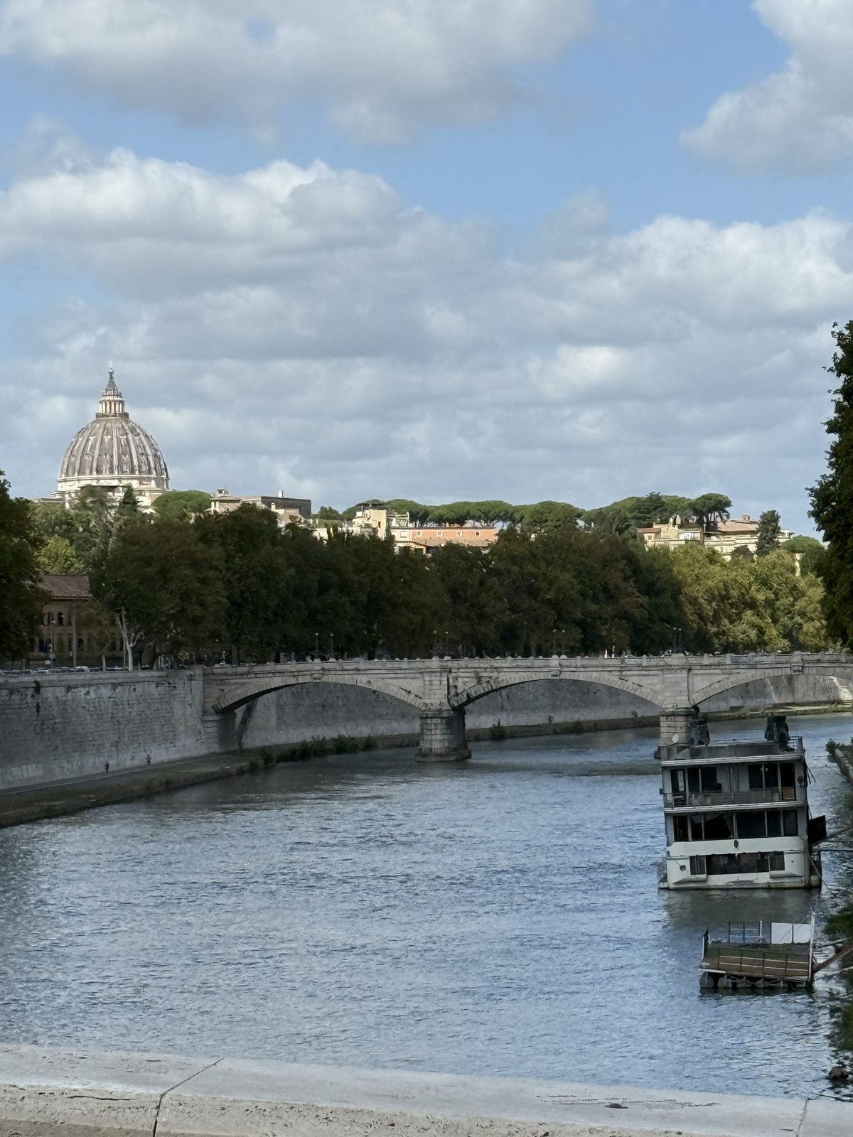 The Tiber river in Rome with a bridge and the dome of St Peters in the distance