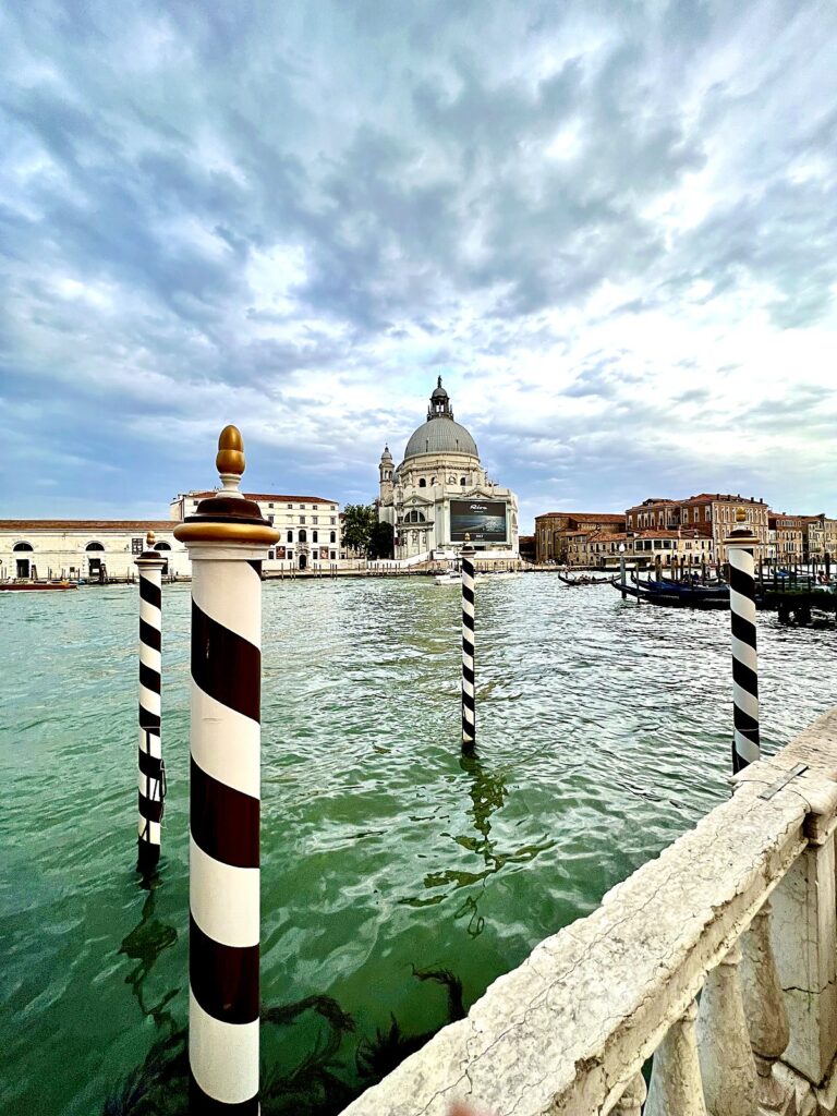 Striped mooring poles and the dome of Santa Maria della Salute across the lagoon in Venice